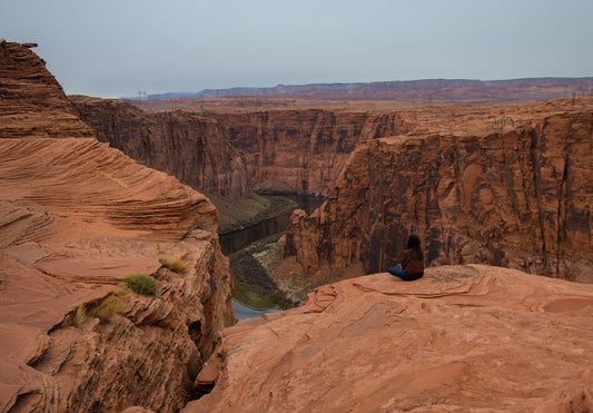 une-personne-assise-sur-une-falaise-surplombant-un-canyon-YNzY_ozCc_c