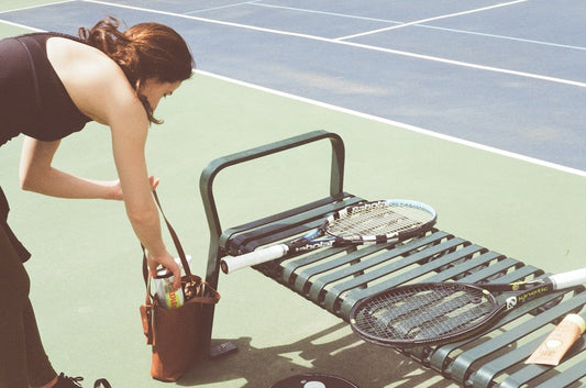 une-femme-se-penche-pour-ramasser-une-raquette-de-tennis-RobJnKFZhcQ